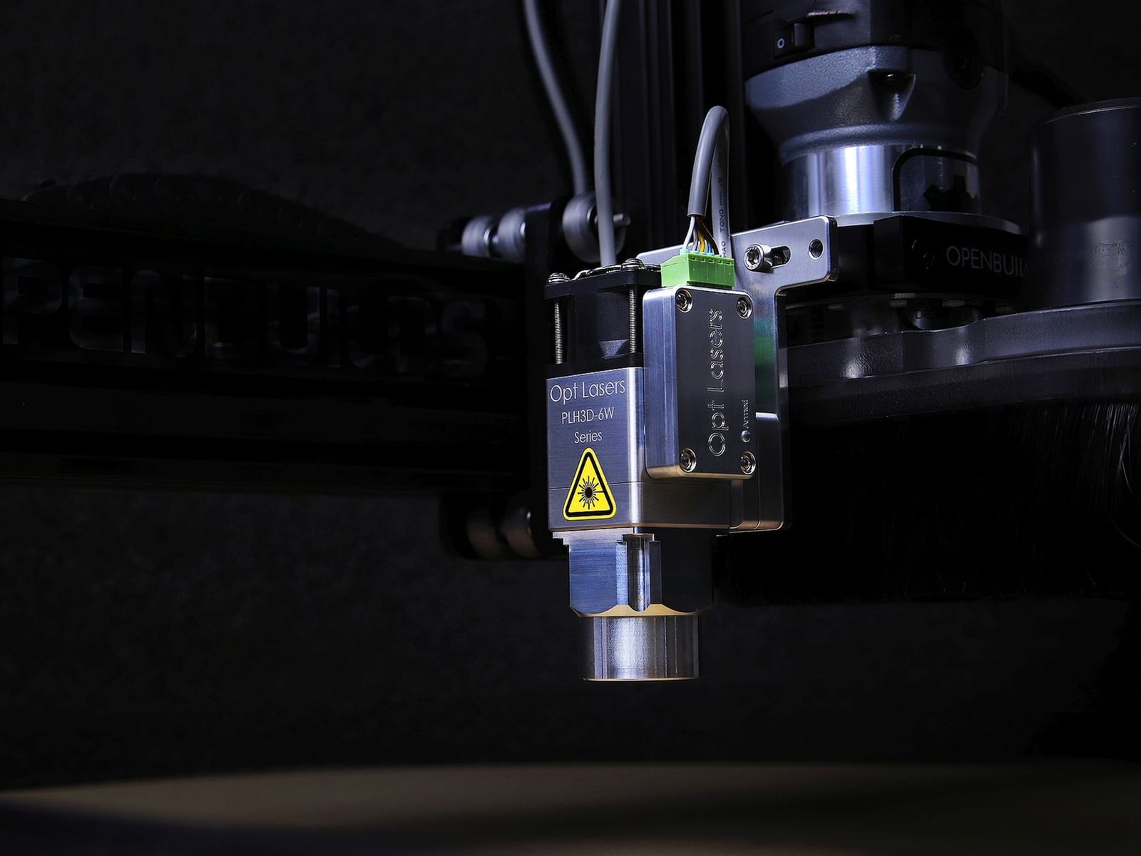 Nahaufnahme einer präzisen Laser-Gravur auf dunklem Walnussholz mit sichtbarem Lichtpunkt.